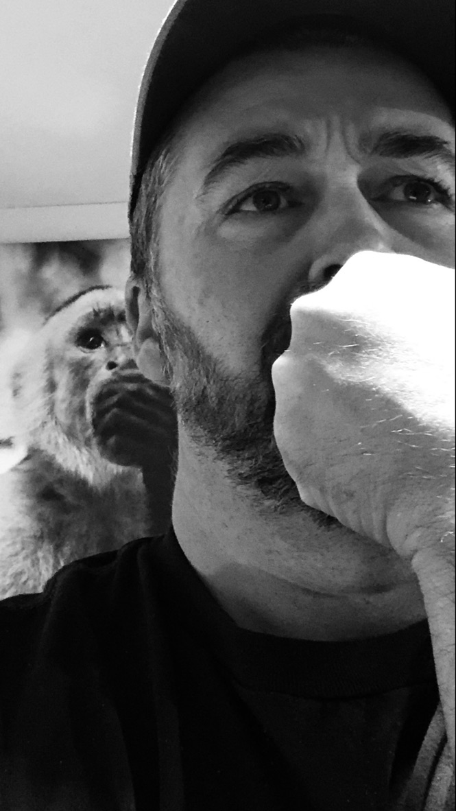 Marc Bourgeois in a thoughtful pose, with a monkey portrait in the background